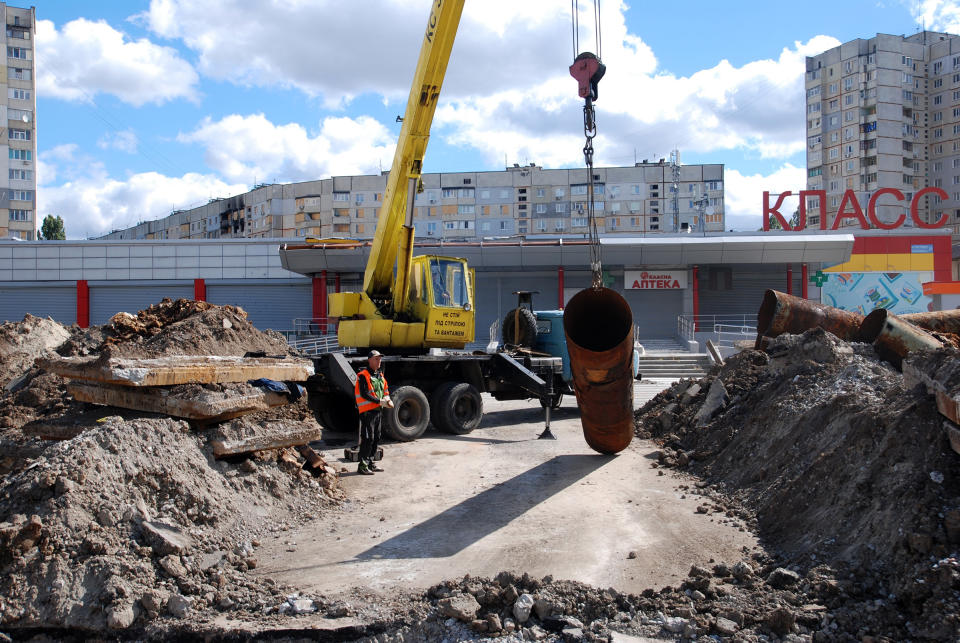 A utility worker stands near a truck crane which lifts an old pipe on Sept. 9, 2022 in Kharkiv, Ukraine. City authorities organized the replacement of heating pipes to reduce heat loss in the Saltivka district, despite daily shelling by Russian troops.<span class="copyright">Oleksandr Lapshyn—Global Images Ukraine/Getty Images</span>