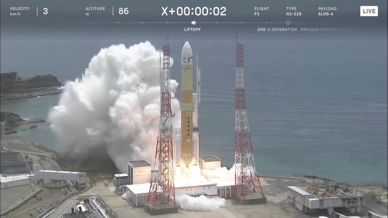  A yellow rocket launches from a seaside pad. 