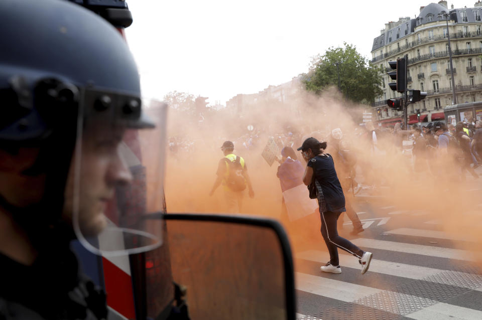 Protestors move away from gas canisters during a demonstration in Paris, France, Saturday, July 31, 2021. Demonstrators gathered in several cities in France on Saturday to protest against the COVID-19 pass, which grants vaccinated individuals greater ease of access to venues. (AP Photo/Adrienne Surprenant)