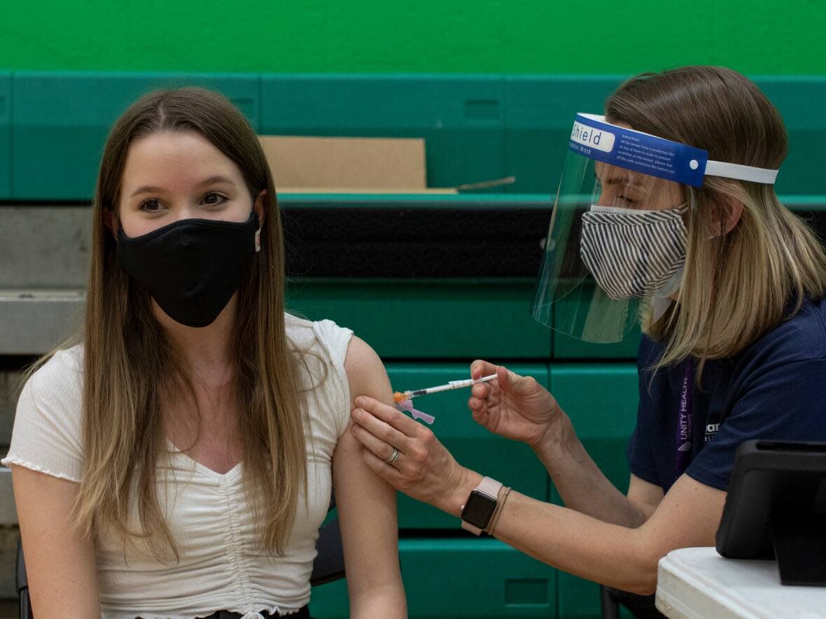 A student, 13, gets her first dose of the Pfizer COVID-19 vaccine at a clinic held at Don Bosco Catholic Secondary School in Toronto earlier this year. (Evan Mitsui/CBC - image credit)