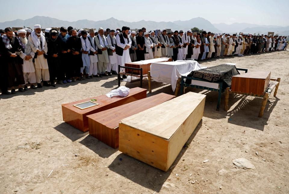 Afghan men offer funeral prayers over the coffins of the victims of Saturday's blast (REUTERS)