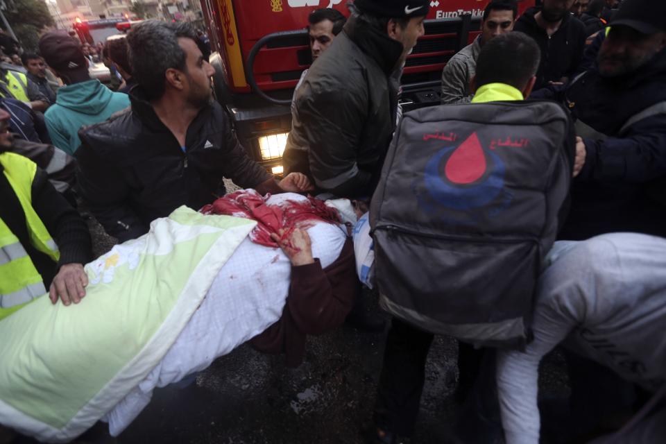 Civil defence personnel help a wounded woman at the site of an explosion in Beirut's southern suburbs January 2, 2014. The powerful explosion in Shi'ite group Hezbollah's southern Beirut stronghold killed three people on Thursday and sent a column of smoke into the sky, a witness said. (REUTERS/Hasan Shaaban)