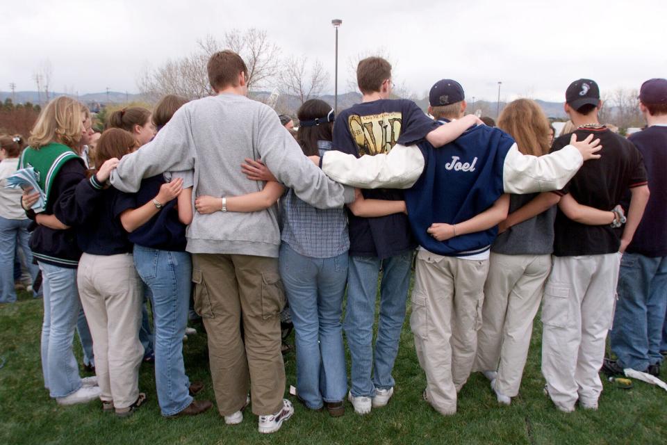 Students stand with arms around each other at an impromptu memorial to students killed at Columbine High School on April 21, 1999.