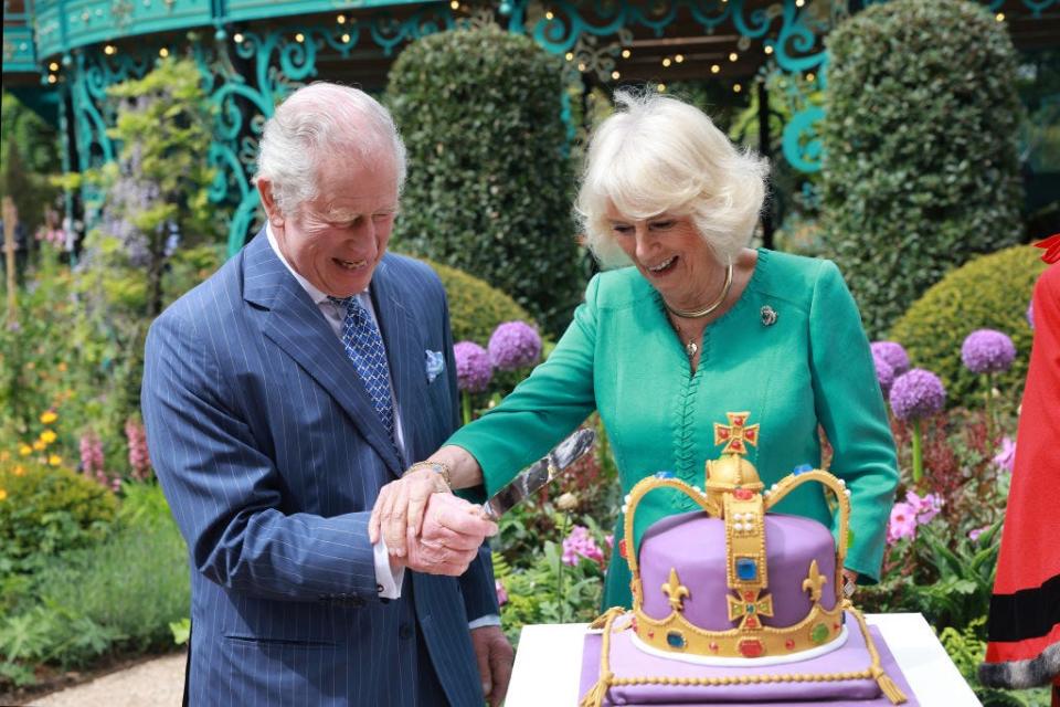 King Charles and Queen Camilla laugh as they cut a cake