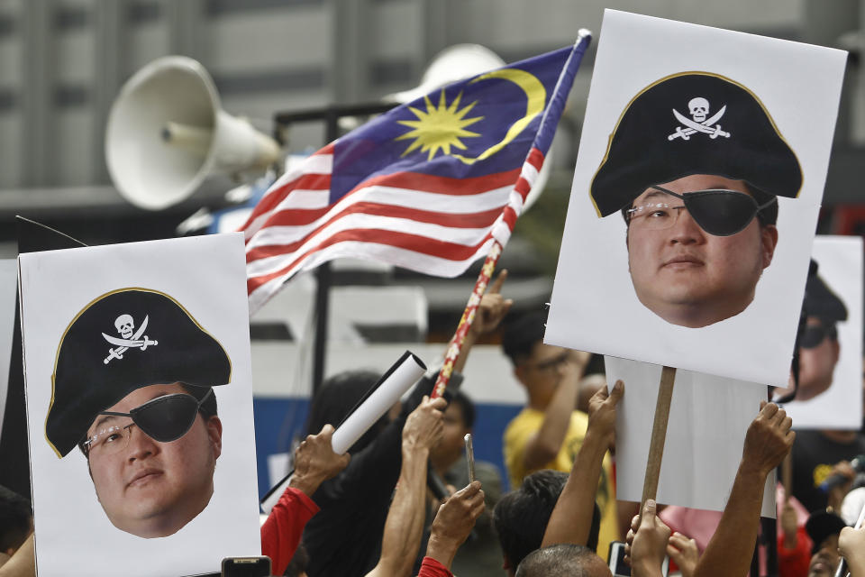 FILE - In this April 14, 2018, file photo, protesters hold portraits of Jho Low illustrated as a pirate during a protest in Kuala Lumpur, Malaysia. The United States Justice Department on Thursday charged the fugitive Malaysian financier in a money laundering and bribery scheme that pilfered billions of dollars from a Malaysian investment fund created to promote economic development projects in that country. The three-count indictment charges Low Taek Jho, who is also known as Jho Low, with misappropriating money from the state-owned fund and using it for bribes and kickbacks to foreign officials, to pay for luxury real estate, art and jewelry in the United States and to fund Hollywood movies, including "The Wolf of Wall Street." (AP Photo/Sadiq Asyraf, File)