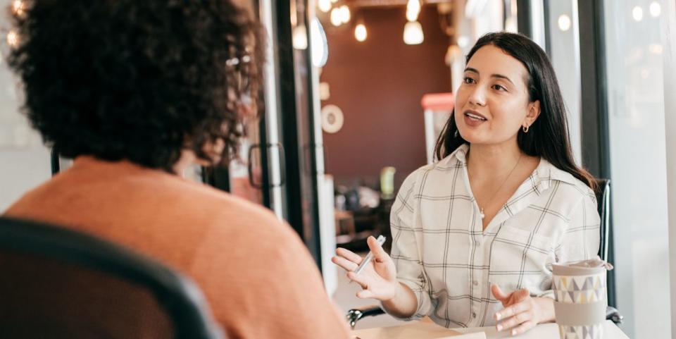 two women sat at a desk and talking in the office