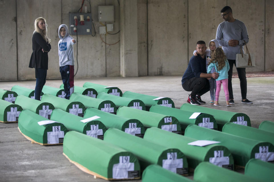 Relatives inspect coffins prepared for burial, in Potocari near Srebrenica, Bosnia, Wednesday, July 10, 2019. The remains of 33 victims of Srebrenica massacre will be buried on July 11, 2019, 24 years after Serb troops overran the eastern Bosnian Muslim enclave of Srebrenica and executed some 8,000 Muslim men and boys, which international courts have labeled as an act of genocide. (AP Photo/Darko Bandic)