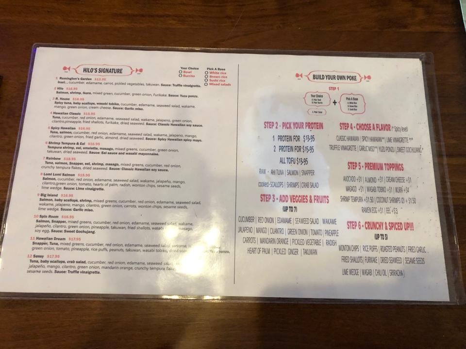 A laminated menu at Hilo Poke & Sushi, featuring "Signature" bowls as well as "Make Your Own" poke options