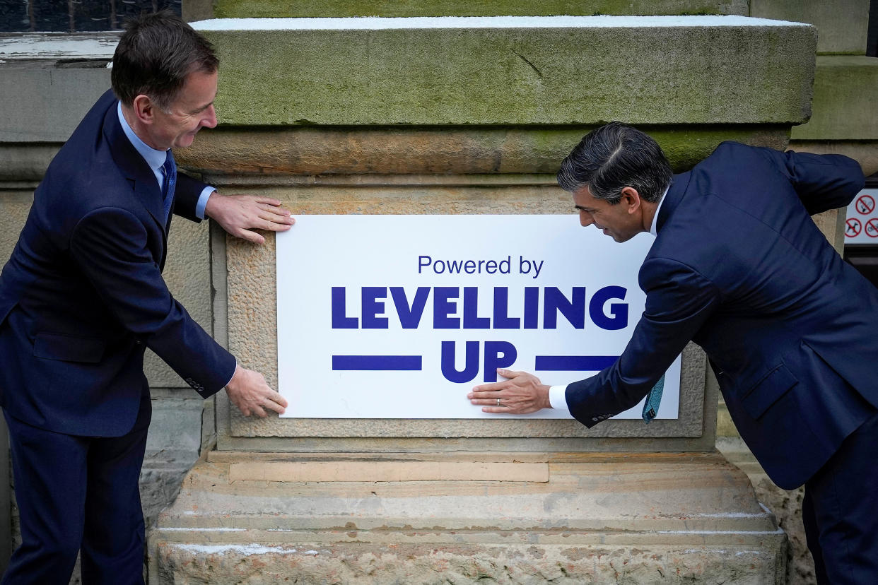 British Prime Minister Rishi Sunak and Chancellor Jeremy Hunt fix a 'Powered By Levelling Up' sign on to Accrington Market Hall during a visit in Accrington, Britain, January 19, 2023.?Christopher Furlong/Pool via REUTERS