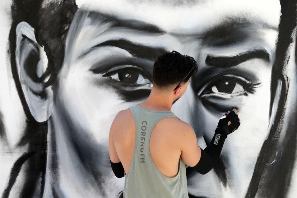 A man paints a mural of Olympic champion boxer Imane Khelif's face.