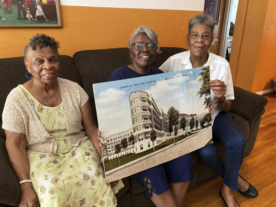 Retired nurses, from left, Jobyna Foster, Yvonne Jones and Zenobia Thompson pose with a rendering of the former Homer G. Phillips Hospital in St. Louis at Jones’ home on Aug. 9, 2022. All three trained and worked at the 660-bed hospital, which served Black residents of St. Louis until it closed in 1979. They are part of a lawsuit aimed at stopping a new three-bed hospital from using the Homer G. Phillips name. (AP Photo/Jim Salter)