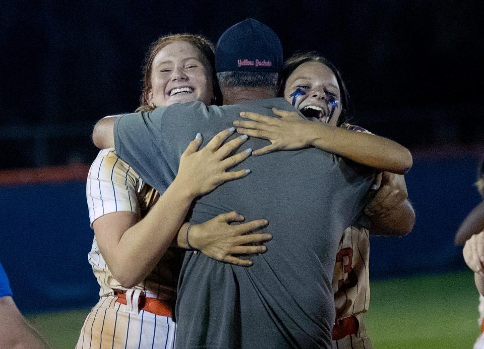 Bartow pitcher Red Oxley and right fielder Destiny Driskell hug head coach Glenn Rutenbar after their victory over Melbourne on Friday night in the Class 6A, Region 3 final.