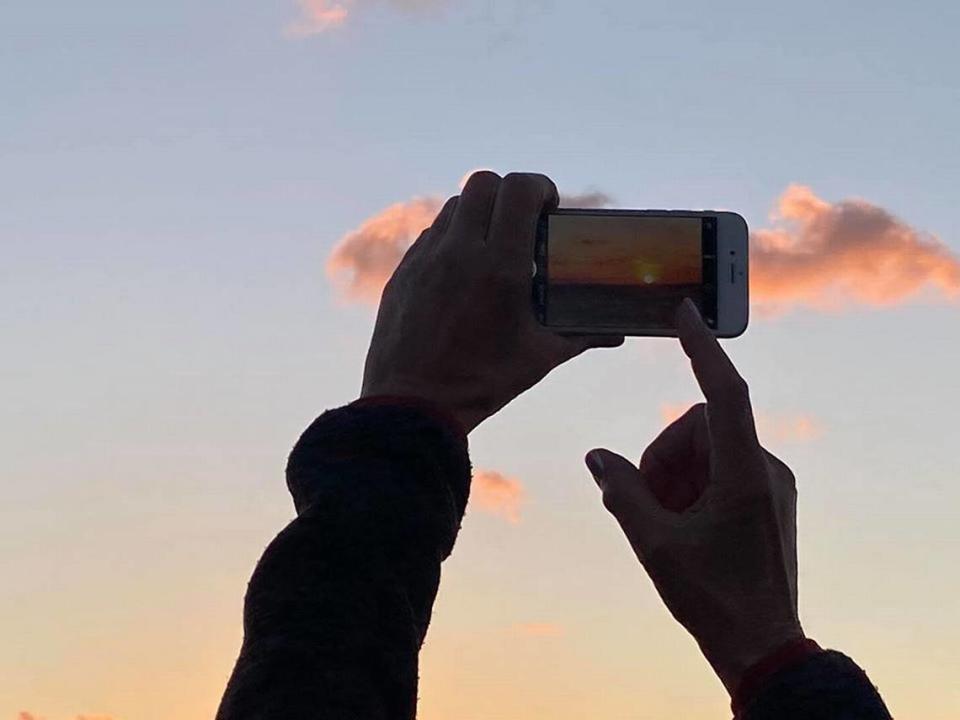 A woman aims for a photo of the sunset at Mallory Square on March 16, 2020.