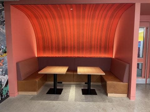 A dining booth surrounded by pink walls.