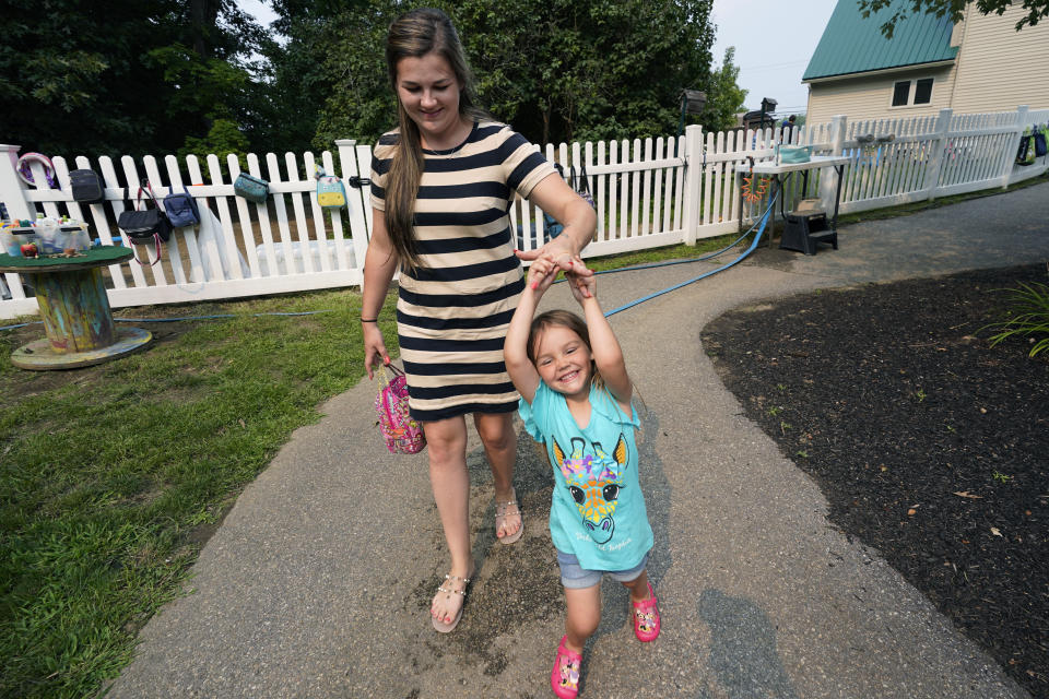 In this July 26, 2021 photo, Brianne Walker leaves A Place To Grow daycare with her 3-year-old daughter, Jeannette, in Brentwood, N.H. Walker and her family have qualified for the expanded child tax credit, part of President Joe Biden's $1.9 trillion coronavirus relief package. "The additional money does help alleviate the pressure," said Walker, 29, who took custody of her two siblings last year after her mother overdosed. The $800 credit will help make up for losses she incurred after quitting a kitchen design job to care for her three children, as well as her two younger brothers. (AP Photo/Elise Amendola)