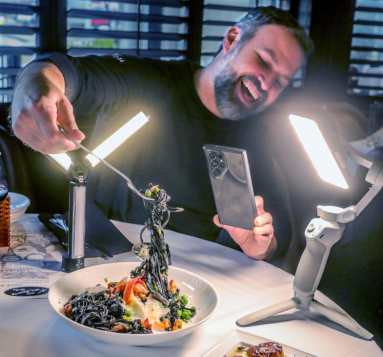 Eat Local Ohio ambassador Abe McCune takes a close up video of a pasta dish at Ken Stewart's Grille on Thursday, Feb. 22, 2024, in Akron, Ohio. [Phil Masturzo/ Beacon Journal]