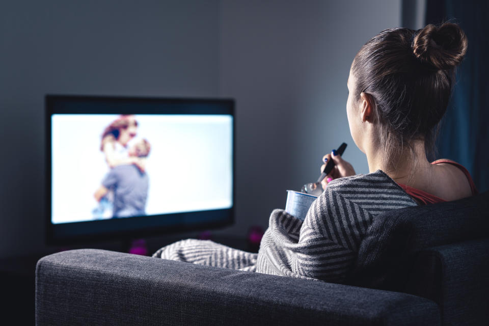 Woman watching tv late and eating food. (Getty Images)