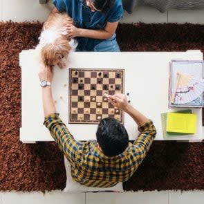 Young Man And Woman Having Fun With Dog While Playing Chess