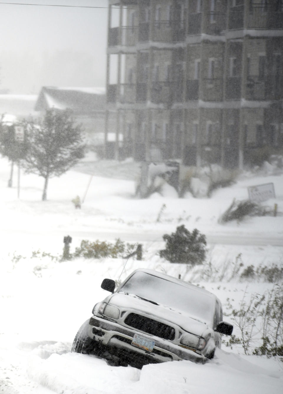 An abandoned SUV is stuck in a snow-filled ditch after the driver slipped off the road near the intersection of North 19th Street and 43rd Ave NE, Friday, Oct. 11, 2019 in Bismarck, N.D. North Dakota Gov. Doug Burgum on Friday activated the state's emergency plan due to what he called a crippling snowstorm that closed major highways and had farmers and ranchers bracing for the potential of huge crop and livestock losses. (Mike McCleary/The Bismarck Tribune via AP)