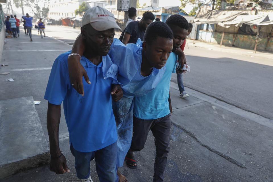 Men help evacuate a man from the General Hospital during gang violence in Port-au-Prince, Haiti, Thursday, Feb. 29, 2024. Gunmen shot at the international airport and other targets in a wave of violence that forced businesses, government agencies and schools to close early. (AP Photo/Odelyn Joseph)