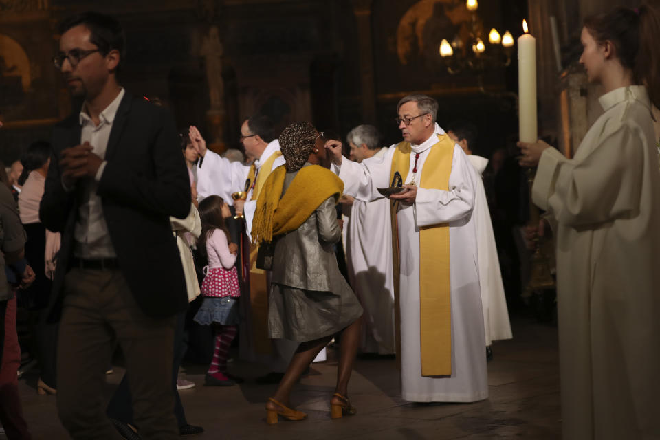 Priests give communion to faithfuls during a Sunday Mass at the grandiose Saint-Eustache church on the Right Bank of the Seine river in Paris, Sunday, April 21, 2019. The archbishop of Paris and Catholics from around France and the world honored the firefighters who saved Notre Dame Cathedral, praying Sunday at a special Easter Mass for a swift reconstruction of the beloved monument. (AP Photo/Francisco Seco)