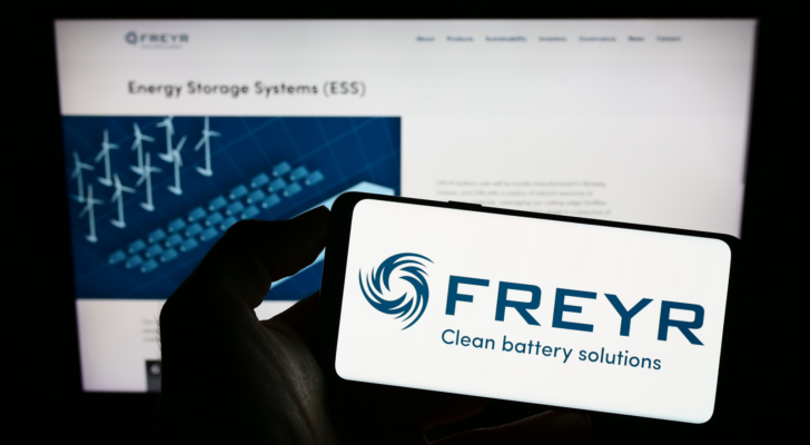 Person holding smartphone with logo of Norwegian battery company Freyr AS (FREY) on screen in front of website. Focus on phone display. Unmodified photo.