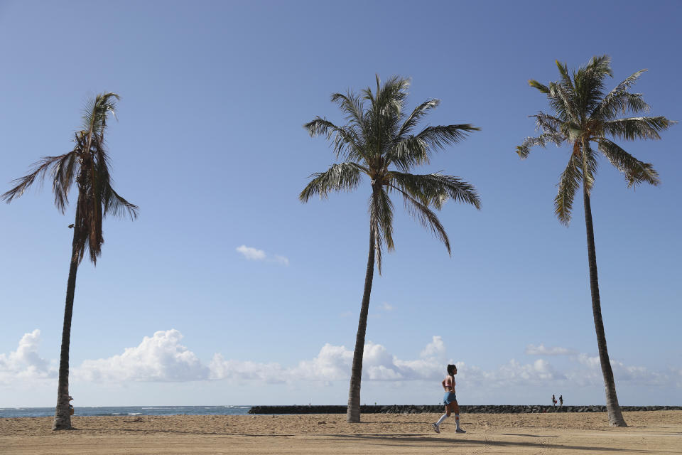 A beachgoer walks down Waikiki Beach, Thursday, Oct. 15, 2020, in Honolulu. A new pre-travel testing program will allow visitors who test negative for COVID-19 to come to Hawaii and avoid two weeks of mandatory quarantine goes into effect Thursday. The pandemic has caused a devastating downturn on Hawaii's tourism-based economy and many are hoping the testing will help the economy rebound. (AP Photo/Marco Garcia)