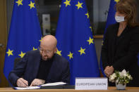 European Council President Charles Michel signs the EU-UK Trade and Cooperation Agreement at the European Council headquarters in Brussels, Wednesday, Dec. 30, 2020. European Union's top officials have formally signed the post-Brexit trade deal sealed with the United Kingdom. European Commission president Ursula von der Leyen and European Council president Charles Michel put pen to paper on Wednesday morning during a brief ceremony in Brussels (Johanna Geron, Pool Photo via AP)