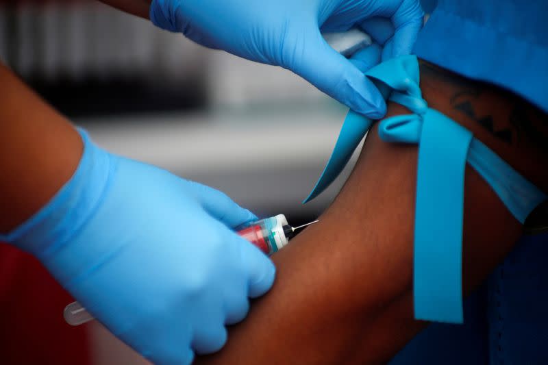 FILE PHOTO: A municipal worker from the Miraflores district of Lima has blood drawn for a test for the coronavirus disease (COVID-19), in Lima