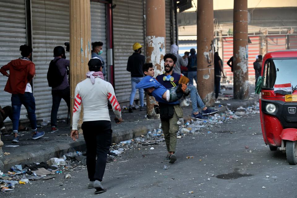A young man is carried away by anti-government protesters gathering on Rasheed Street during clashes with security forces in Baghdad, Iraq, Tuesday, Nov. 26, 2019. (AP Photo/Khalid Mohammed)