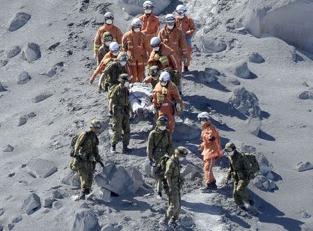 Japan Self-Defense Force (JSDF) soldiers and firefighters carry an injured person near a crater of Mt. Ontake, which straddles Nagano and Gifu prefectures in this September 28, 2014 photo taken and released by Kyodo. REUTERS/Kyodo