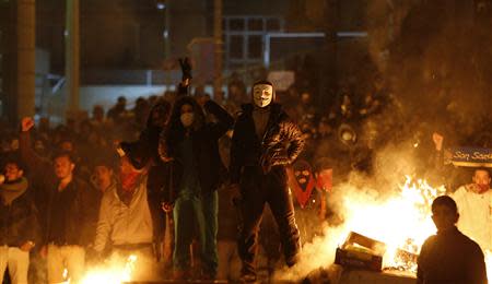 Anti-government protesters stand behind a barricade that they set on fire during a demonstration in Ankara March 12, 2014. REUTERS/Umit Bektas