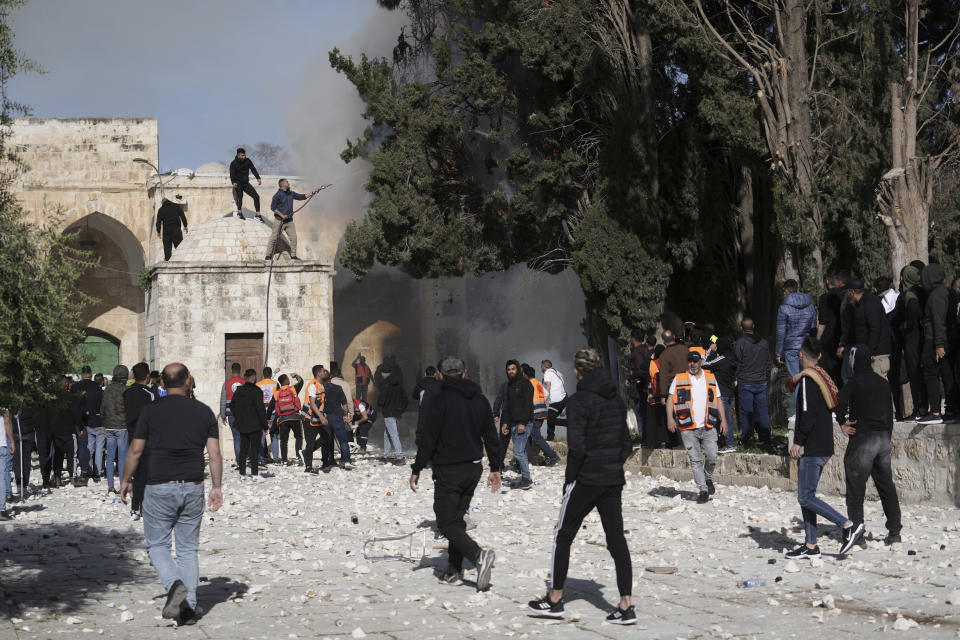 Palestinians work to extinguish a tree that caught fire as Israeli police clashed with protesters at the Al Aqsa Mosque compound, in Jerusalem's Old City, Friday, April 22, 2022. (AP Photo/Mahmoud Illean)