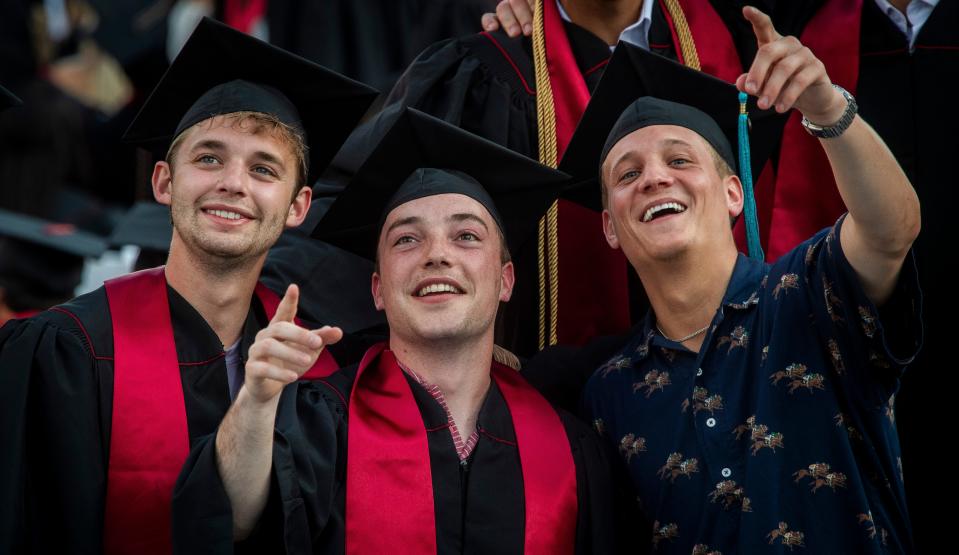 Joseph Mattei, left, Steven Solts, middle, and Jack Yankosky point at a name on the running graduate scroll on the scoreboard during Indiana University's 195th undergraduate commencement proceedings at Memorial Stadium on Saturday, May 4, 2024.