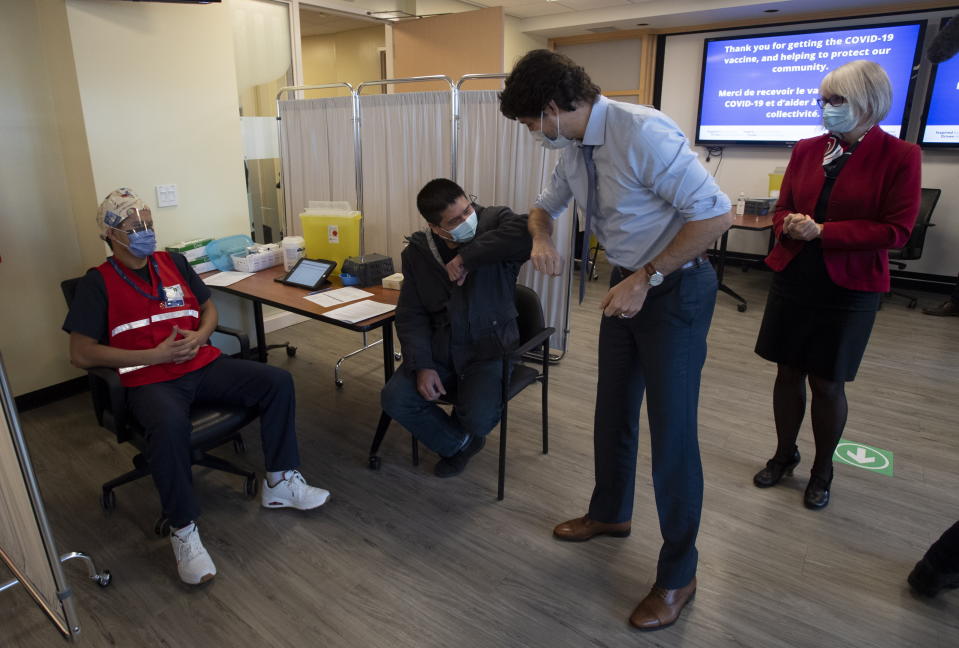 Canada Prime Minister Justin Trudeau and a man who had just received the Pfizer-BioNTech COVID-19 vaccine elbow bump as the Prime Minister toured a vaccinations clinic at the Ottawa Hospital with Minister of Health Patty Hajdu, Tuesday, Dec. 15, 2020, in Ottawa. (Adrian Wyld/The Canadian Press via AP)