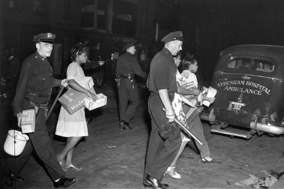 Police lead women to patrol cars in the Harlem area of New York, on Aug. 2, 1943, during clashes with police following the shooting of a policeman and six civilians. The unrest was sparked by the shooting of a black soldier by a white policeman. (AP Photo)