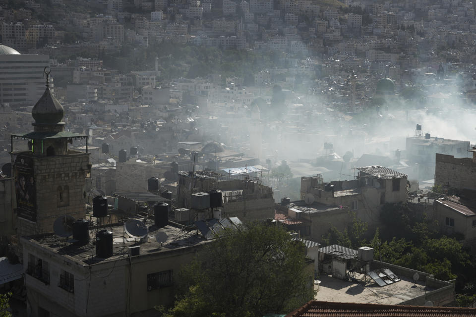 Smoke rises during a raid by Israeli security forces in the occupied West Bank city of Nablus, Thursday, May 4, 2023. The Israeli military says it has killed three Palestinians wanted for an attack last month on a car near a Jewish West Bank settlement that killed a British-Israeli mother and two of her daughters. The military says a fierce gunbattle erupted when the army entered the heart of the flashpoint city of Nablus early Thursday. (AP Photo/Majdi Mohammed)