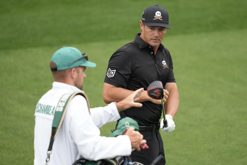 Bryson DeChambeau hands his driver to his caddie on the eighth hole during a practice round in preparation for the Masters golf tournament at Augusta National Golf Club Tuesday, April 9, 2024, in Augusta, Ga. (AP Photo/Ashley Landis)