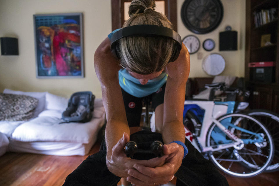 In this undated photo, three-time Ironman world champion Mirinda Carfrae puts in a long indoor training session ng in the rental house she shares with her husband, elite triathlete Tim O'Donnell, and their 1-year-old daughter Isabelle in Lawrence, Kan. The new parents are heading to the Ironman world championships in Kona, Hawaii, next month. (Talbot Cox via AP)