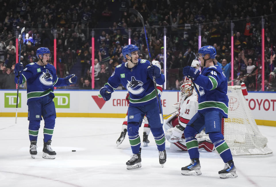 Vancouver Canucks' Ilya Mikheyev, center, Elias Pettersson, right, and Sam Lafferty, left, celebrate Mikheyev's goal against Carolina Hurricanes goalie Antti Raanta during the second period of an NHL hockey game Saturday, Dec. 9, 2023, in Vancouver, British Columbia. (Darryl Dyck/The Canadian Press via AP)