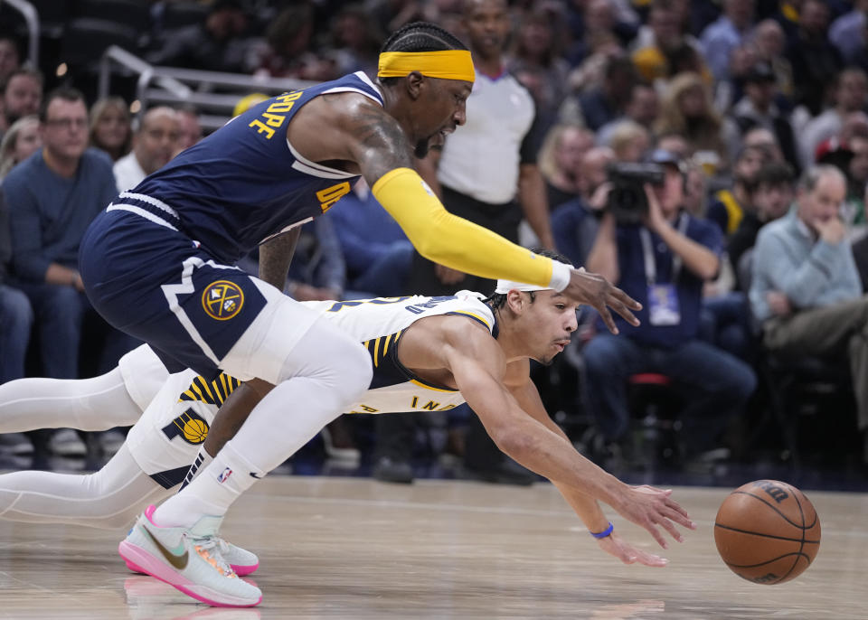 Denver Nuggets' Kentavious Caldwell-Pope, top, and Indiana Pacers' Andrew Nembhard scramble for the ball during the first half of an NBA basketball game Wednesday, Nov. 9, 2022, in Indianapolis. (AP Photo/Darron Cummings)