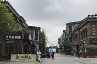 A store employee in a protectively suit waits for customers outside a re-opened retail street in Wuhan in central China's Hubei province on Monday, March 30, 2020. Shopkeepers in the city at the center of China's virus outbreak were reopening Monday but customers were scarce after authorities lifted more of the anti-virus controls that kept tens of millions of people at home for two months. (AP Photo/Olivia Zhang)