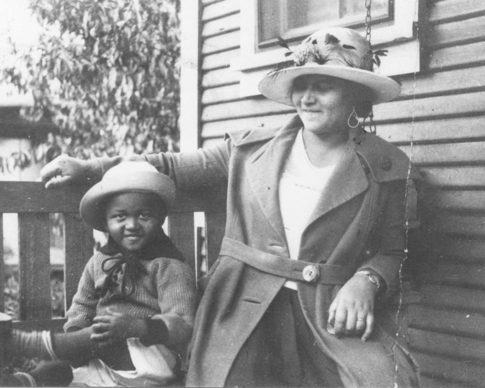 This photo provided by the Department of Special Collections, McFarlin Library, The University of Tulsa shows an African American woman and girl sitting on a porch swing, both dressed in coats and hats, by the side of a house. Provenance is unknown; however, it is believed that these photos were taken in Tulsa, Okla. prior to the Tulsa Race Massacre. (Department of Special Collections, McFarlin Library, The University of Tulsa via AP)