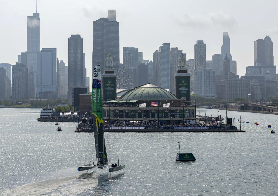 In a photo provided by SailGP, Australia SailGP Team helmed by Tom Slingsby cross the finish line in front of Navy Pier to win the first race on Race Day 1 of the Rolex United States Sail Grand Prix on Friday, June 16, 2023, in Chicago. (Simon Bruty/SailGP via AP)