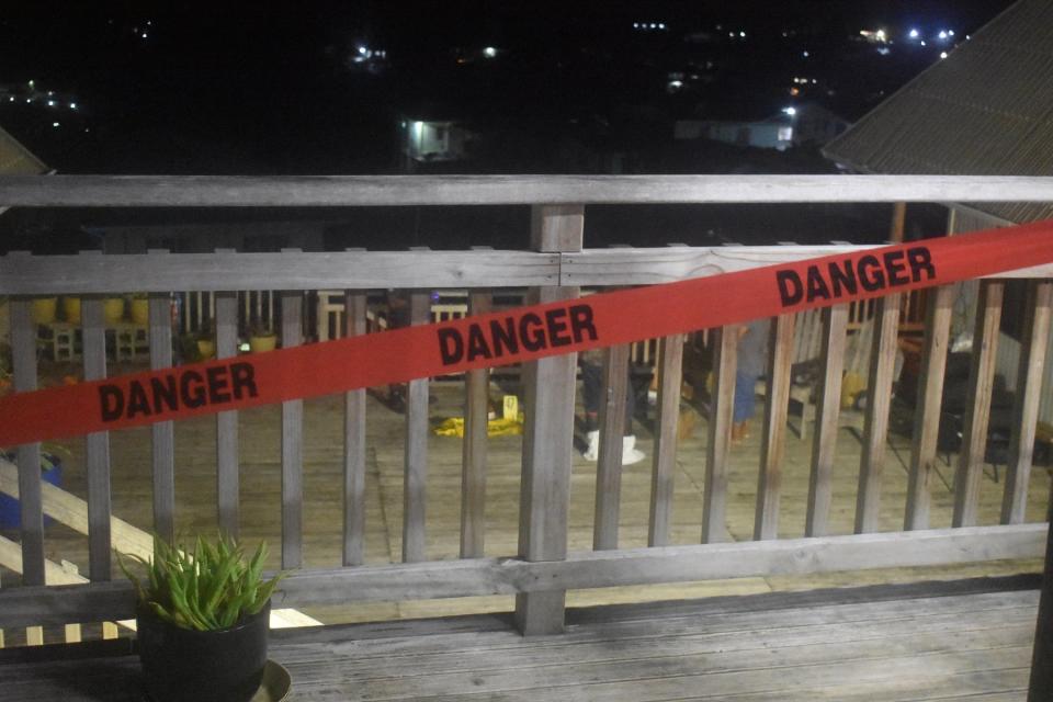 A photo of the scene with tape that reads 'DANGER' strapped to a balcony railing.