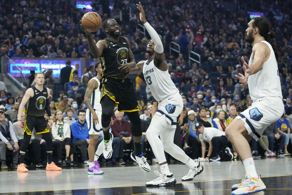 Golden State Warriors forward Draymond Green passes the ball while defended by Memphis Grizzlies forward Jaren Jackson Jr. during the first half of an NBA basketball game in San Francisco, Sunday, Dec. 25, 2022. (AP Photo/Godofredo A. Vásquez)