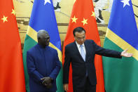 FILE - Chinese Premier Li Keqiang shows the way to Solomon Islands Prime Minister Manasseh Sogavare, left, as they attend a signing ceremony at the Great Hall of the People in Beijing on Oct. 9, 2019. China’s Foreign Minister Wang Yi is visiting the South Pacific with a 20-person delegation this week in a display of Beijing's growing military and diplomatic presence in the region. (Thomas Peter/Pool Photo via AP, File)