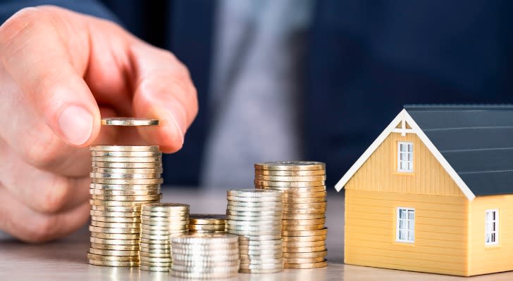 Image shows a person counting stacks of coins on a table next to a model home. Property can be one type of asset that is passed on in generational transfer of wealth.