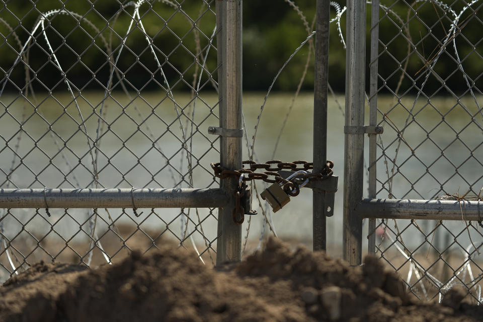 A gate on pecan farm of Hugo and Magali Urbina has been bulldozed, locked and lined with concertina wire along the Rio Grande, near Eagle Pass, Texas, Monday, July 7, 2023. Texas Republican Gov. Greg Abbott has escalated measures to keep migrants from entering the U.S. He's pushing legal boundaries along the border with Mexico to install razor wire, deploy massive buoys on the Rio Grande and bulldozing border islands in the river. (AP Photo/Eric Gay)