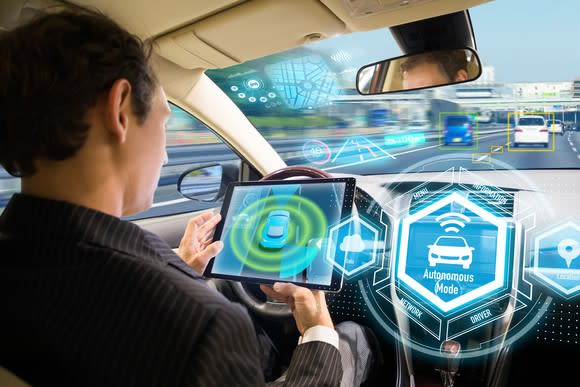 Man on a tablet device in a self-driving vehicle.